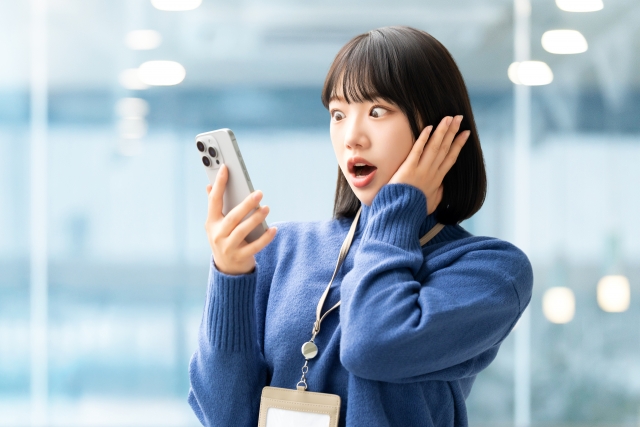 スマホを見て驚く女性