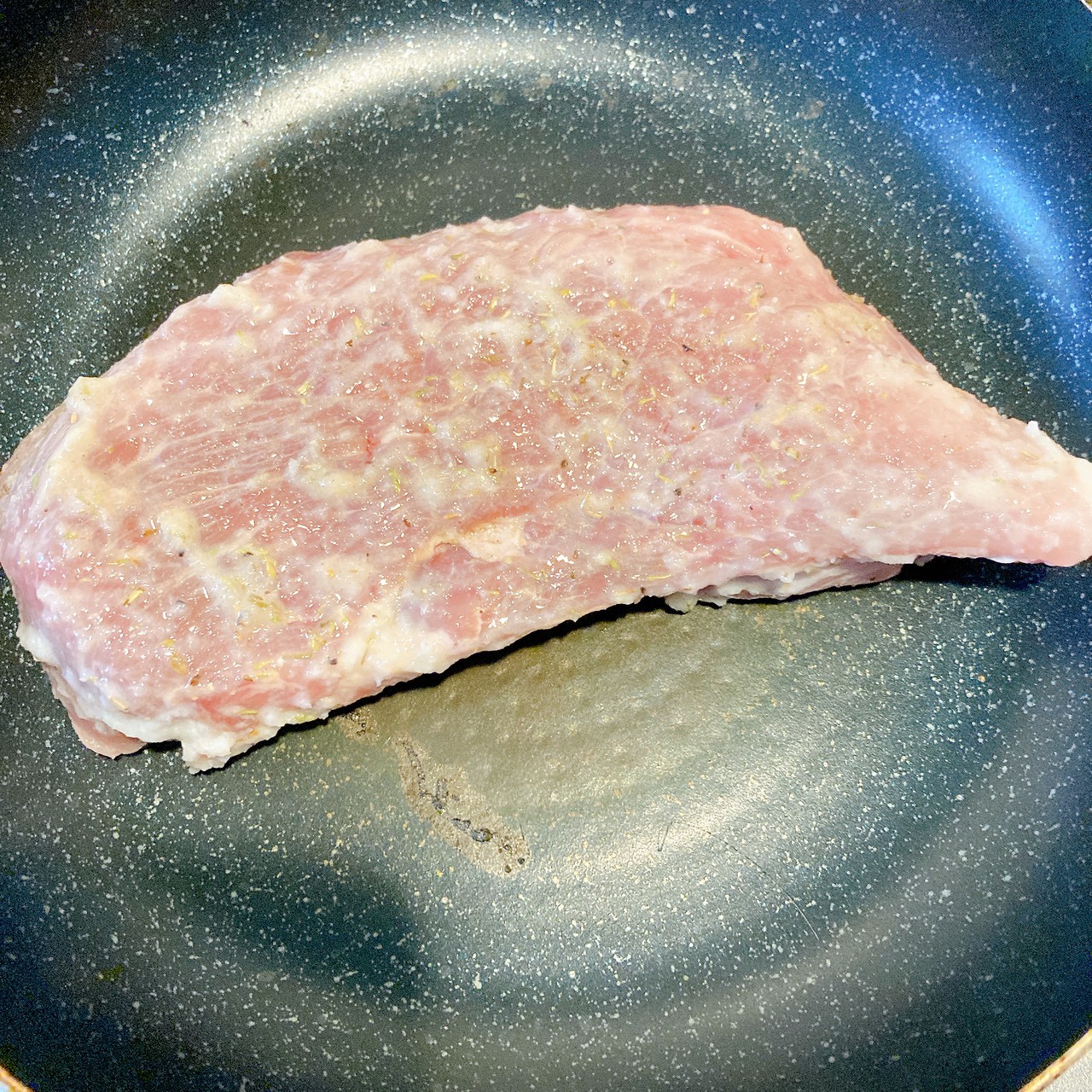 調味料とニンニクが塗られた塊肉がフライパンで焼かれてる