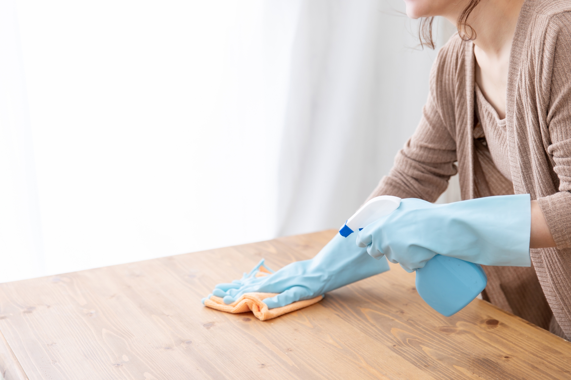 テーブルを洗剤と雑巾で拭いている女性