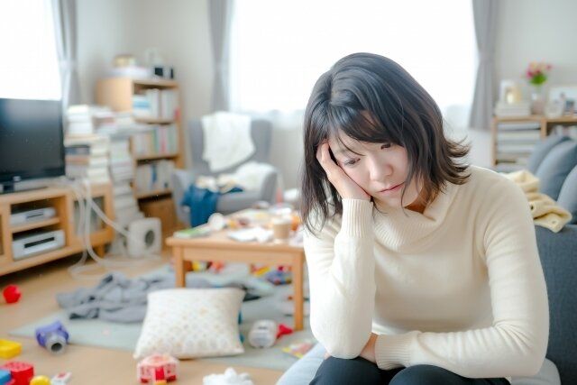 散らかった部屋に悩む女性