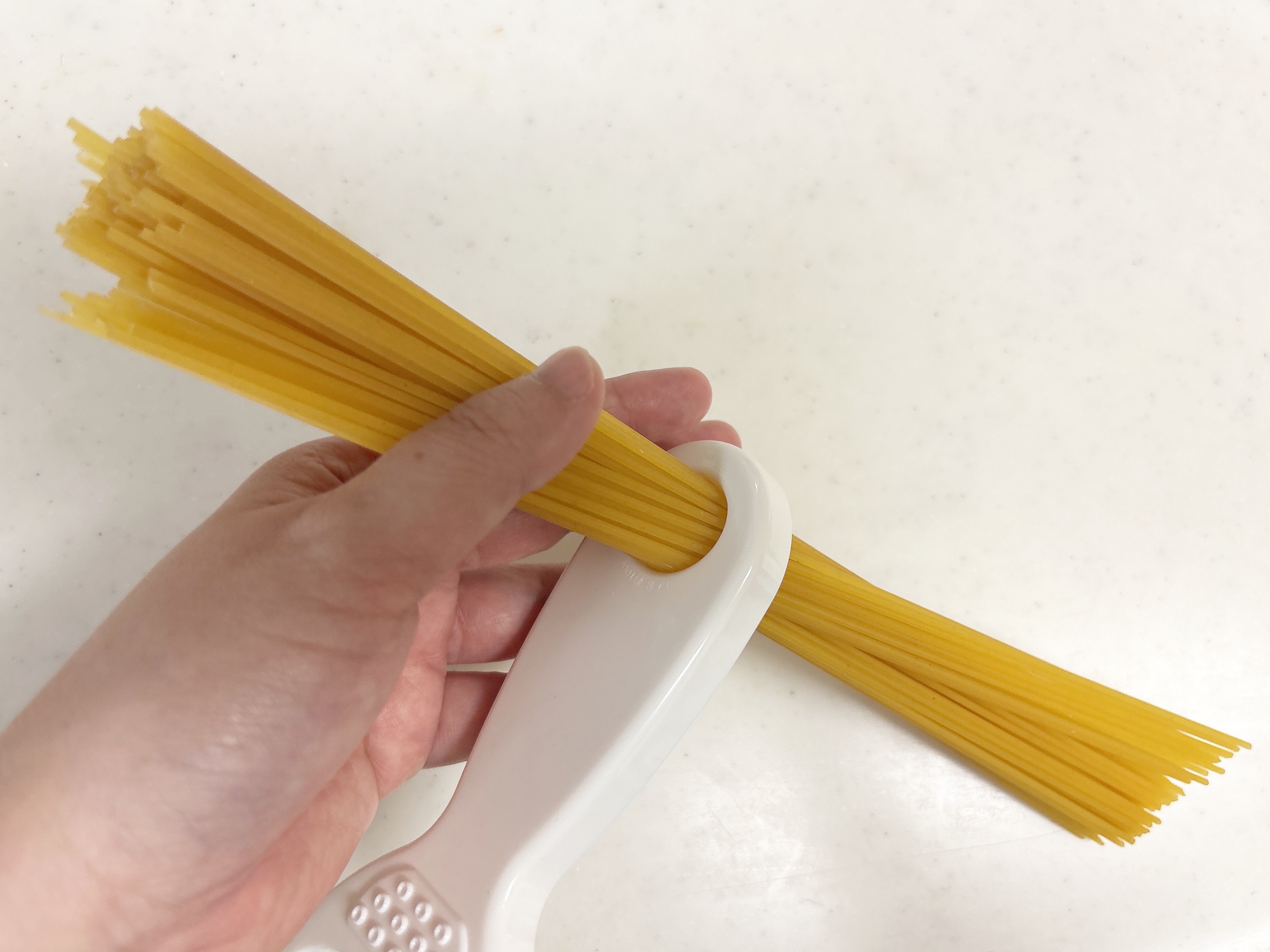 ピーラーでパスタを計っている