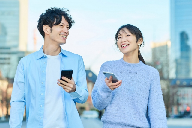 男女がスマホを持って微笑んでいる様子