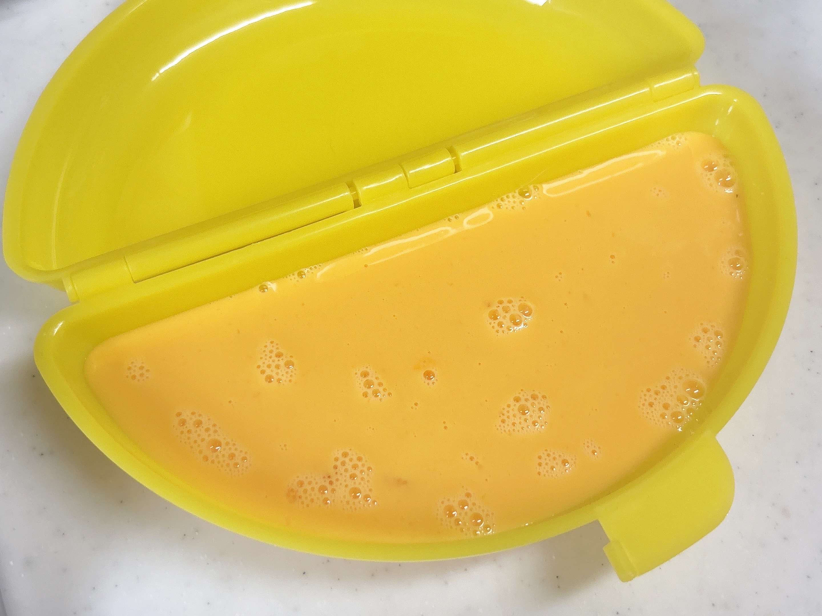 電子レンジで簡単！オムレツの容器の片側に卵をいれた