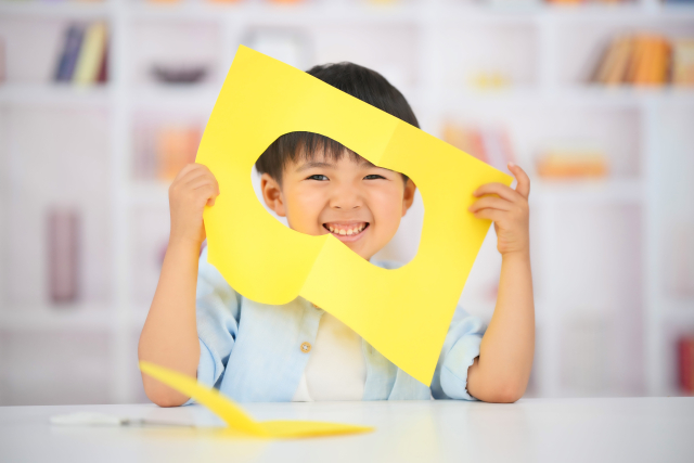 色画用紙の間から顔をのぞかせている子ども