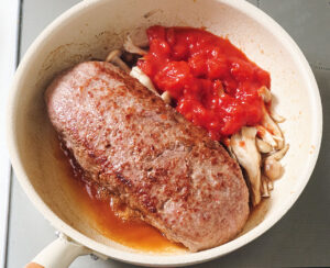 肉だねを焼いてるフライパンの空いてる所にソースの材料を入れている様子