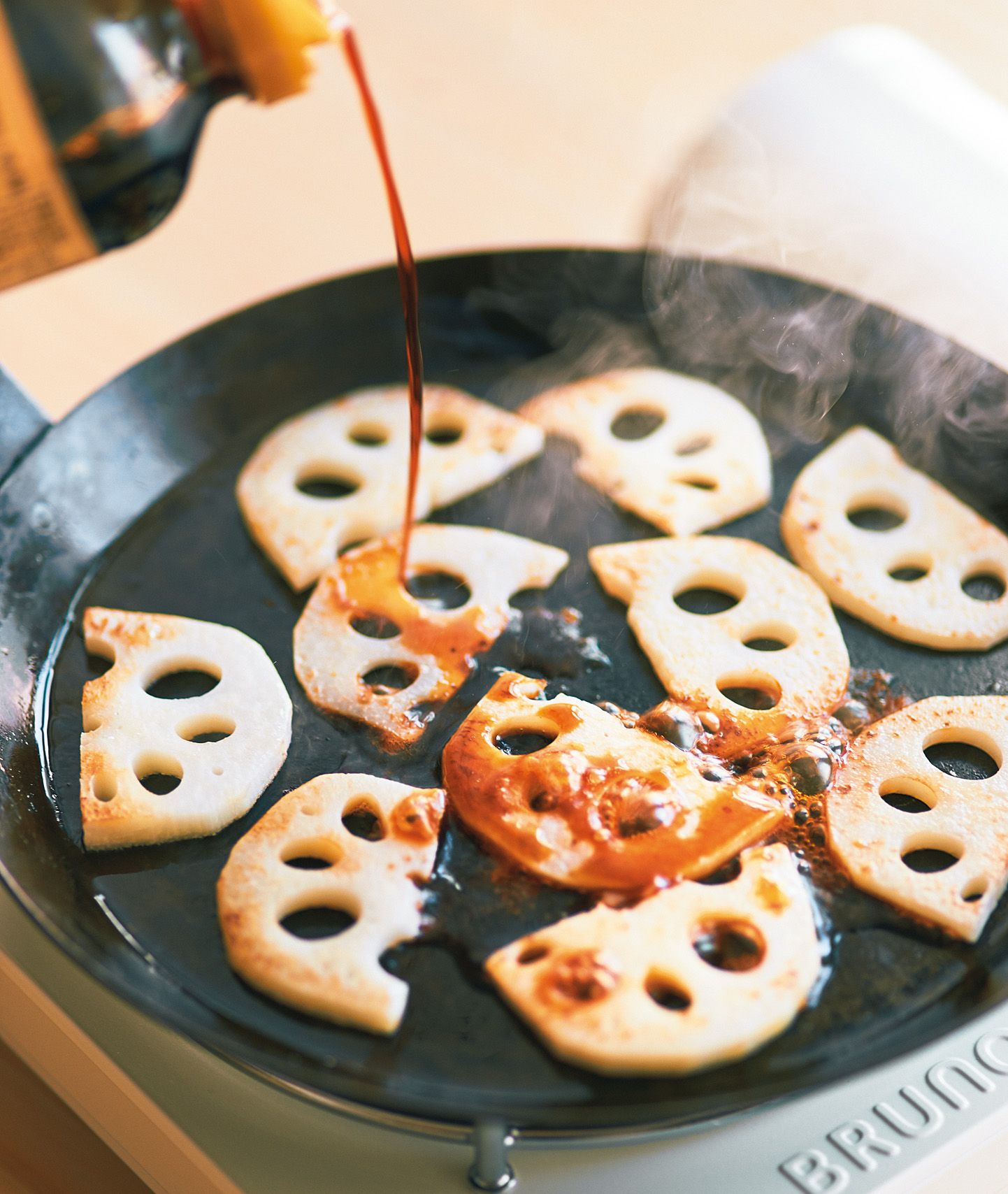 フライパンで焼いている蓮根にしょうゆを入れている様子