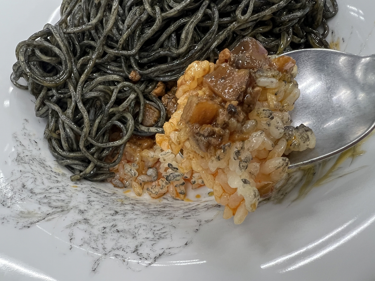 黒麺の中に旨肉味噌とガーリックライスが入っている